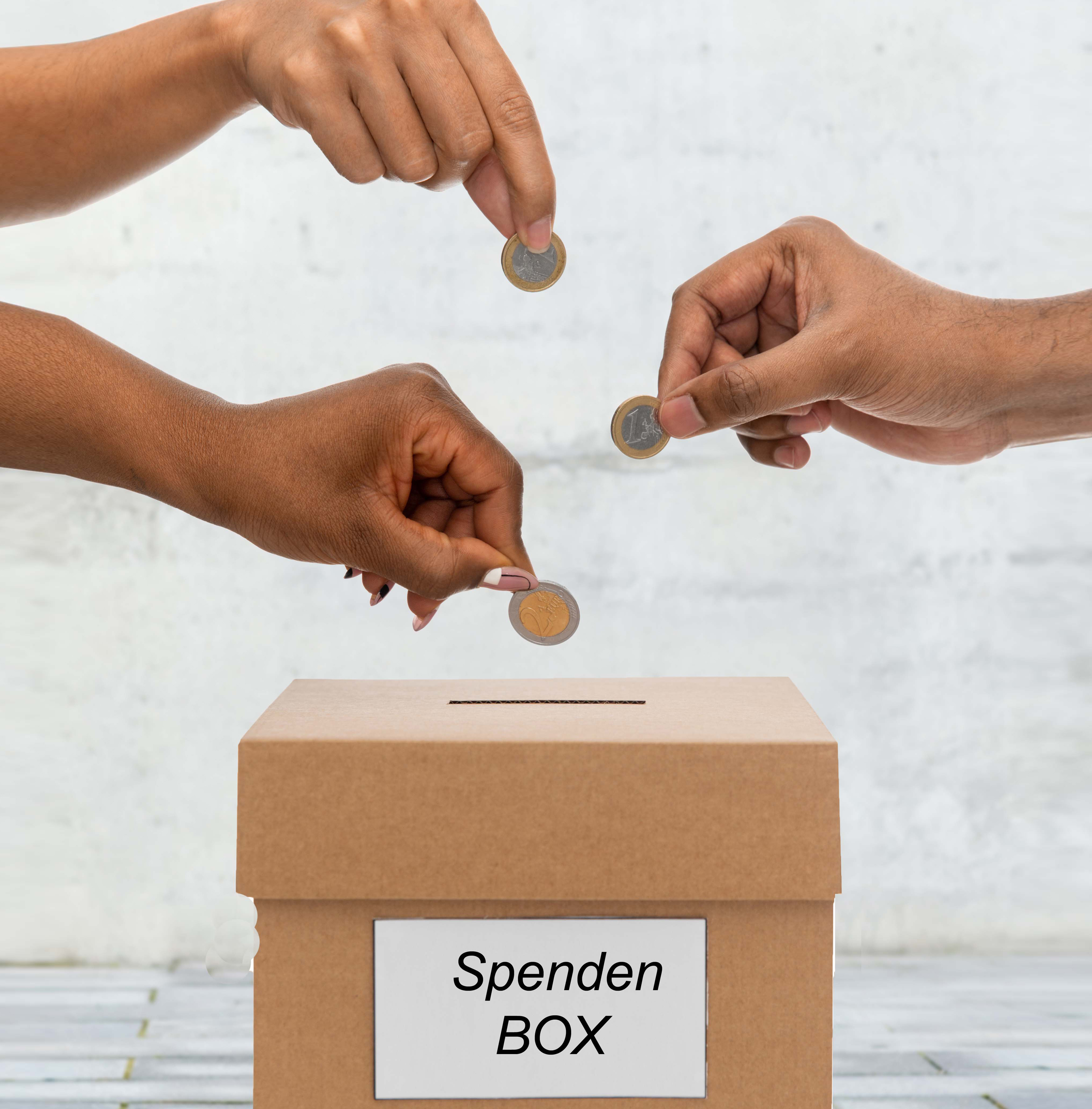 Das Bild zeigt 3 Hände, die Geld in eine Spendenbox werfen.