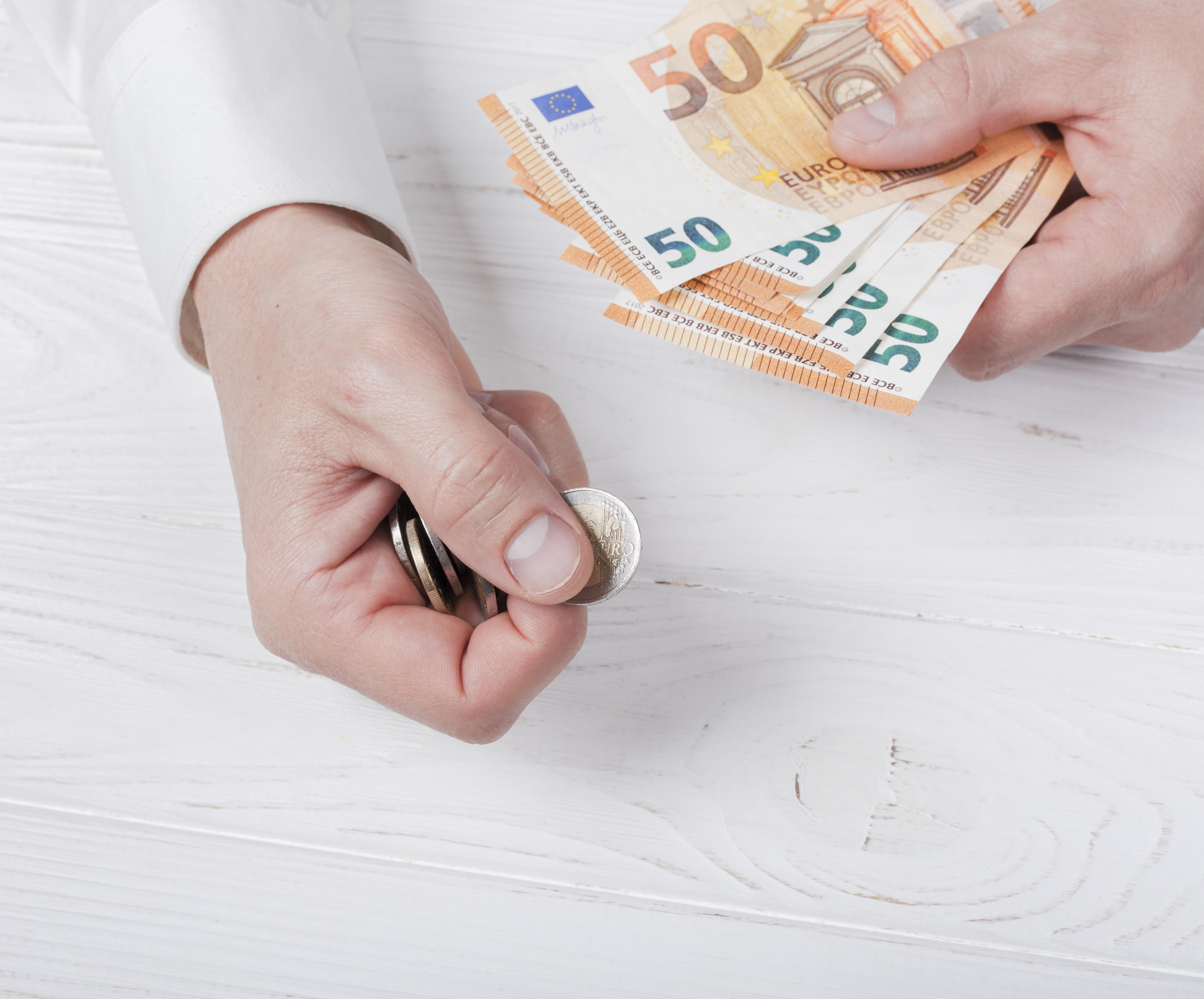 Das Bild zeigt in Großaufnahme 2 Hände, die Geld auszahlen.